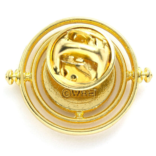 Image du badge Time Turner posé sur un tissu sombre mettant en valeur ses reflets métalliques