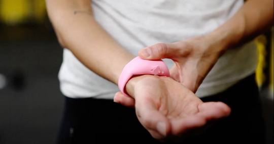 Bracelet SQUEEZYBAND jaune posé sur une surface blanche avec le tube de gel intégré