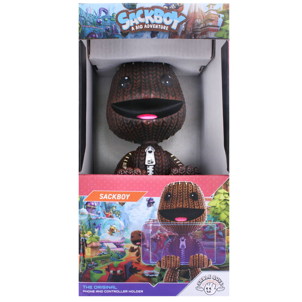 Présentation du support Cable Guy Sackboy sur un bureau de gamer avec manettes PlayStation et Xbox