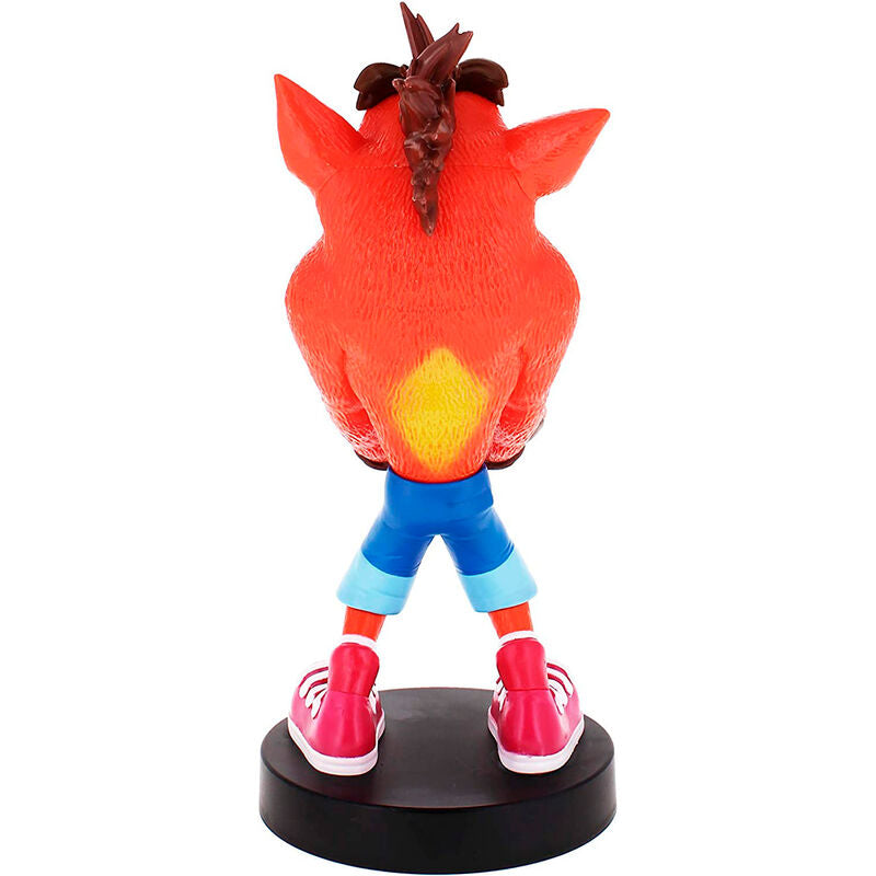 Support chargeur de manettes et smartphones Crash Bandicoot installé sur une table de salon gaming avec plusieurs accessoires