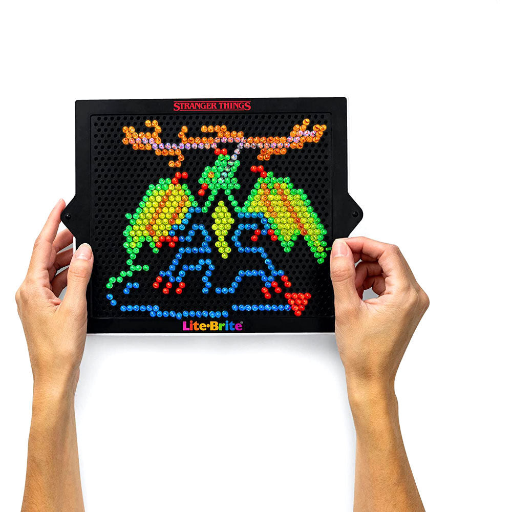 Enfant jouant au jeu Stranger Things Lite Brite, créant une image lumineuse unique.
