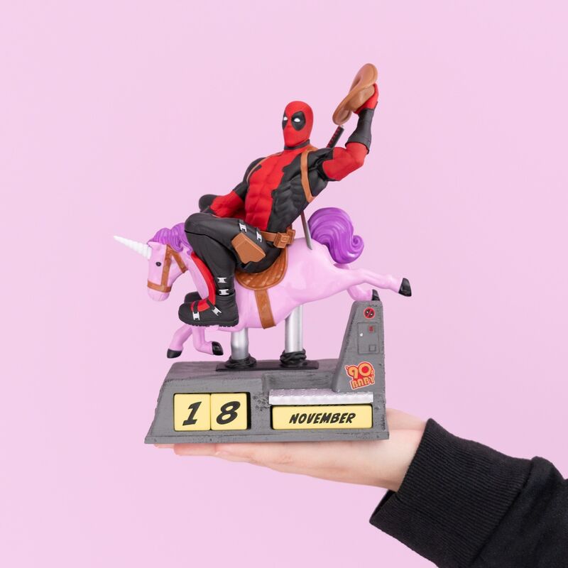 Calendrier Deadpool Marvel posé sur un bureau décoré avec accessoires geek