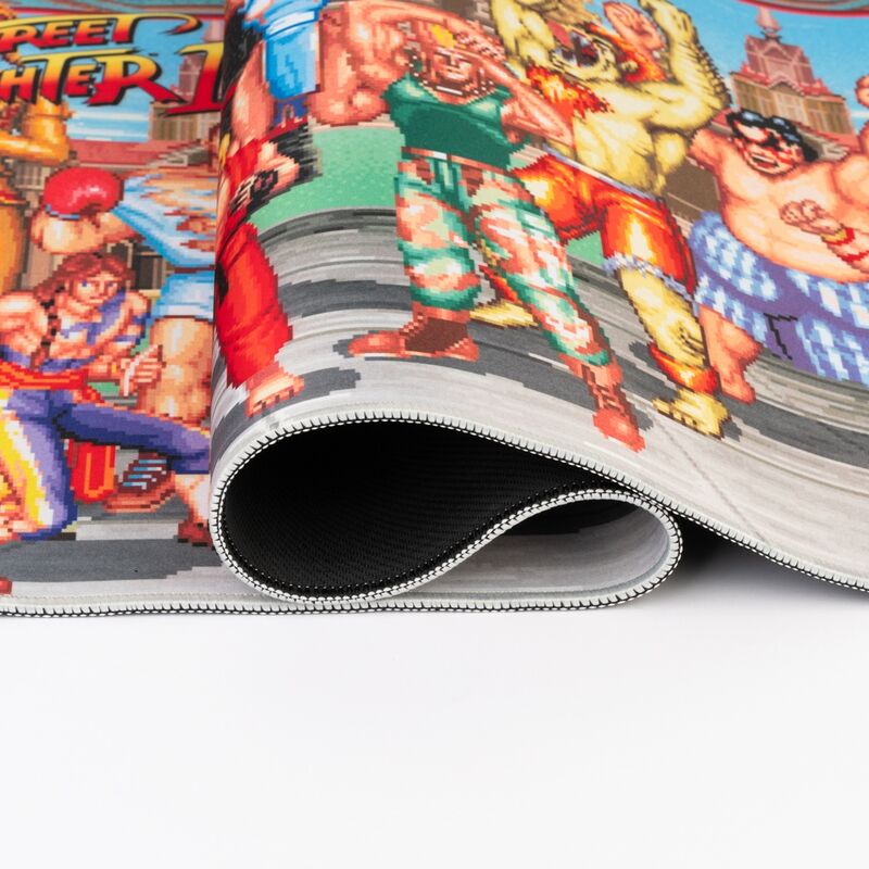 Présentation du tapis Street Fighter ERIK dans un environnement gaming avec éclairage et accessoires pour une ambiance immersive.