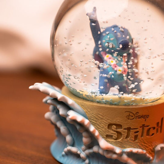 Boule à neige Disney Stitch posée sur une étagère décorative avec fond flou