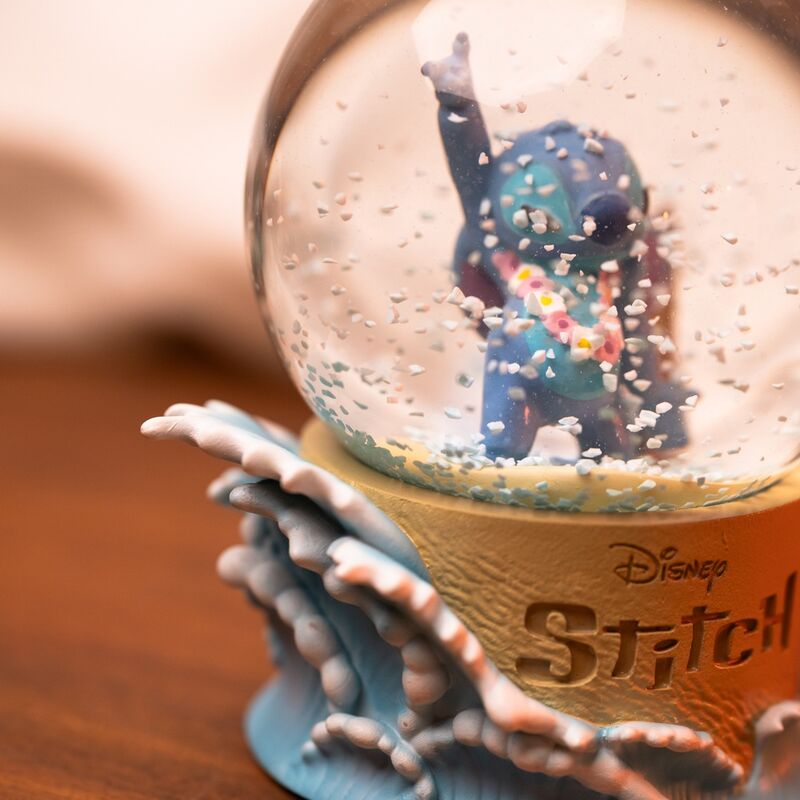 Boule à neige Disney Stitch posée sur une étagère décorative avec fond flou