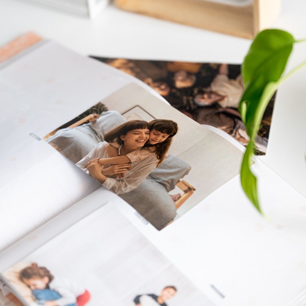 Présentation de l'album posé sur une table entouré de photos souvenirs