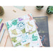 Album photo Around The World ouvert sur une table en bois avec des photos de voyage