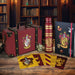 Bouteille en métal aux couleurs Gryffindor et porte-clés assorti posés à côté de la malette sur une surface claire.