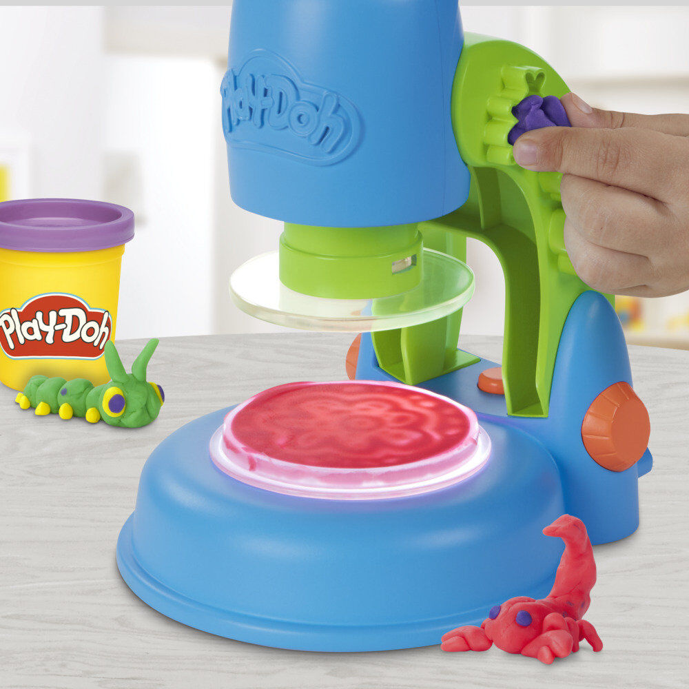 Main d'enfant manipulant la pâte à modeler pour créer un microbe coloré