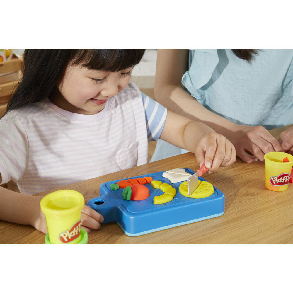 Enfant souriant créant des aliments en pâte à modeler avec le kit