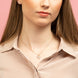 Ensemble collier et boucles d'oreilles Minnie en or rose exposé sur fond neutre, mettant en valeur les détails du ruban