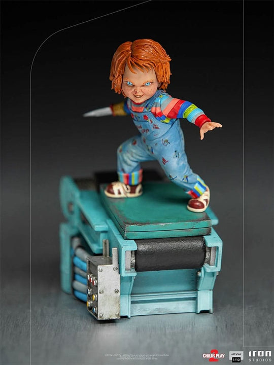 Vue rapprochée de la base de la statuette Chucky, avec des éléments de décor